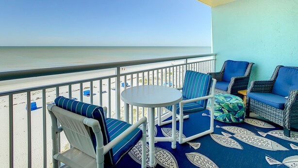 A balcony with a view of the beach, featuring wicker furniture and a round table. - Chateaux 403-Direct Gulf Front Condominium (Indian Shores)