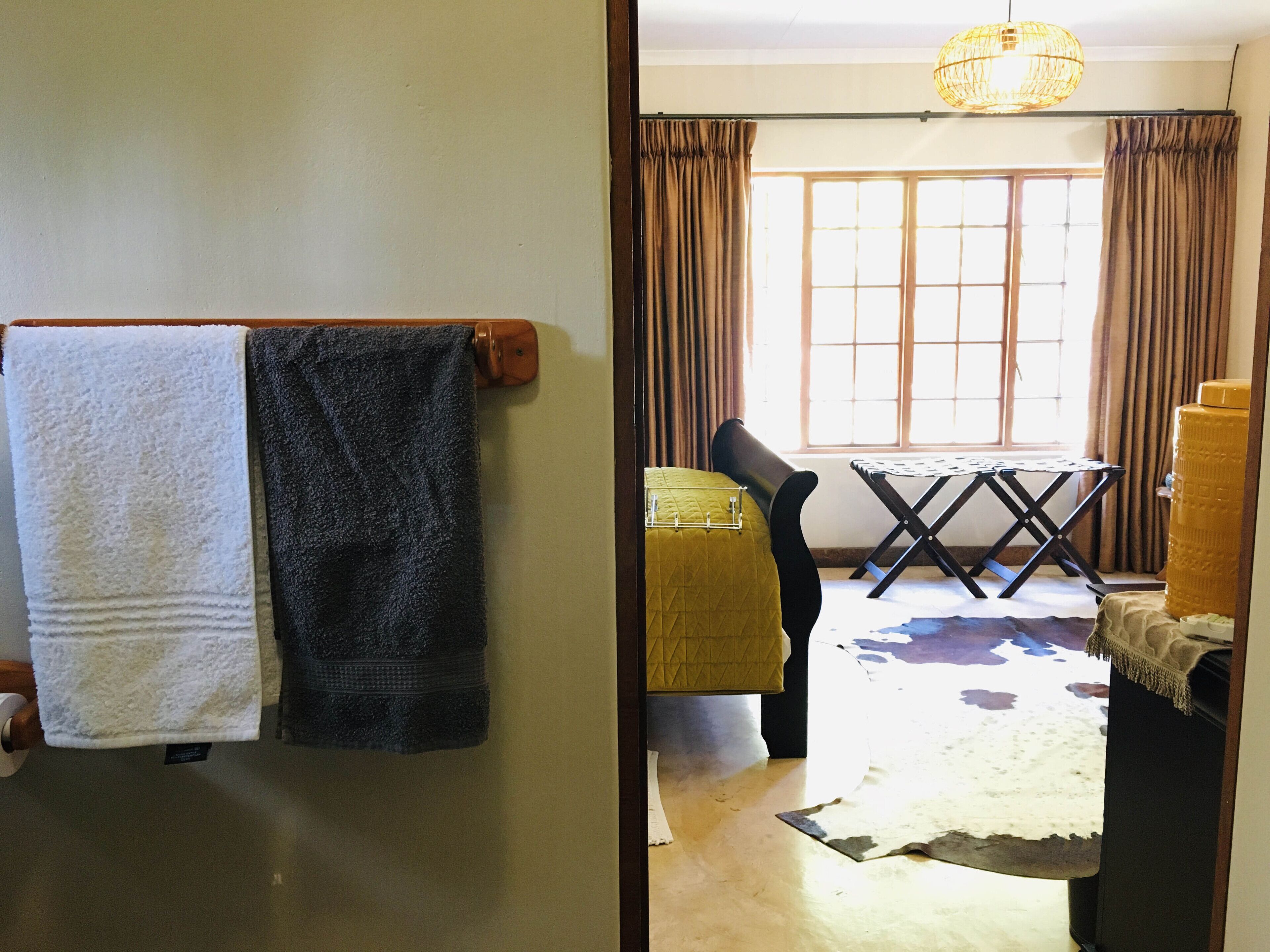 A room with a bed, a window with curtains, a table, and a chair.