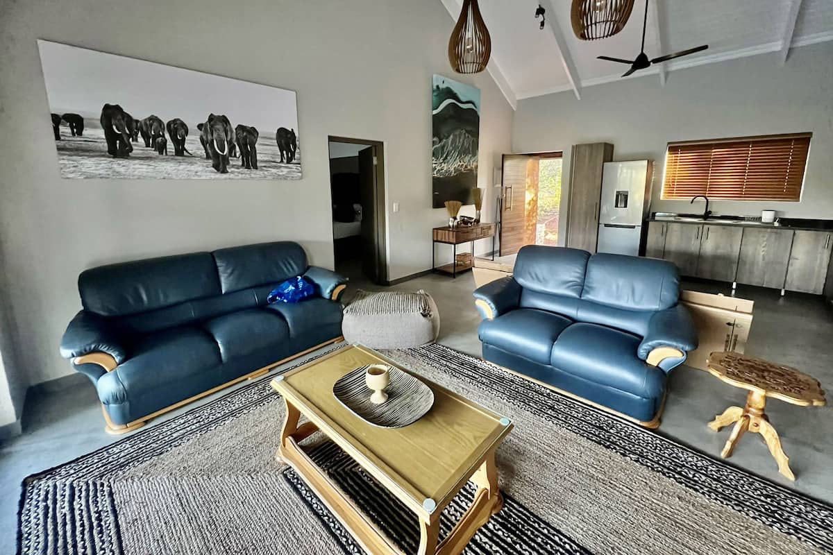 Ein modernes Wohnzimmer mit zwei blauen Sofas, einem Holztisch und einem gemusterten Teppich.