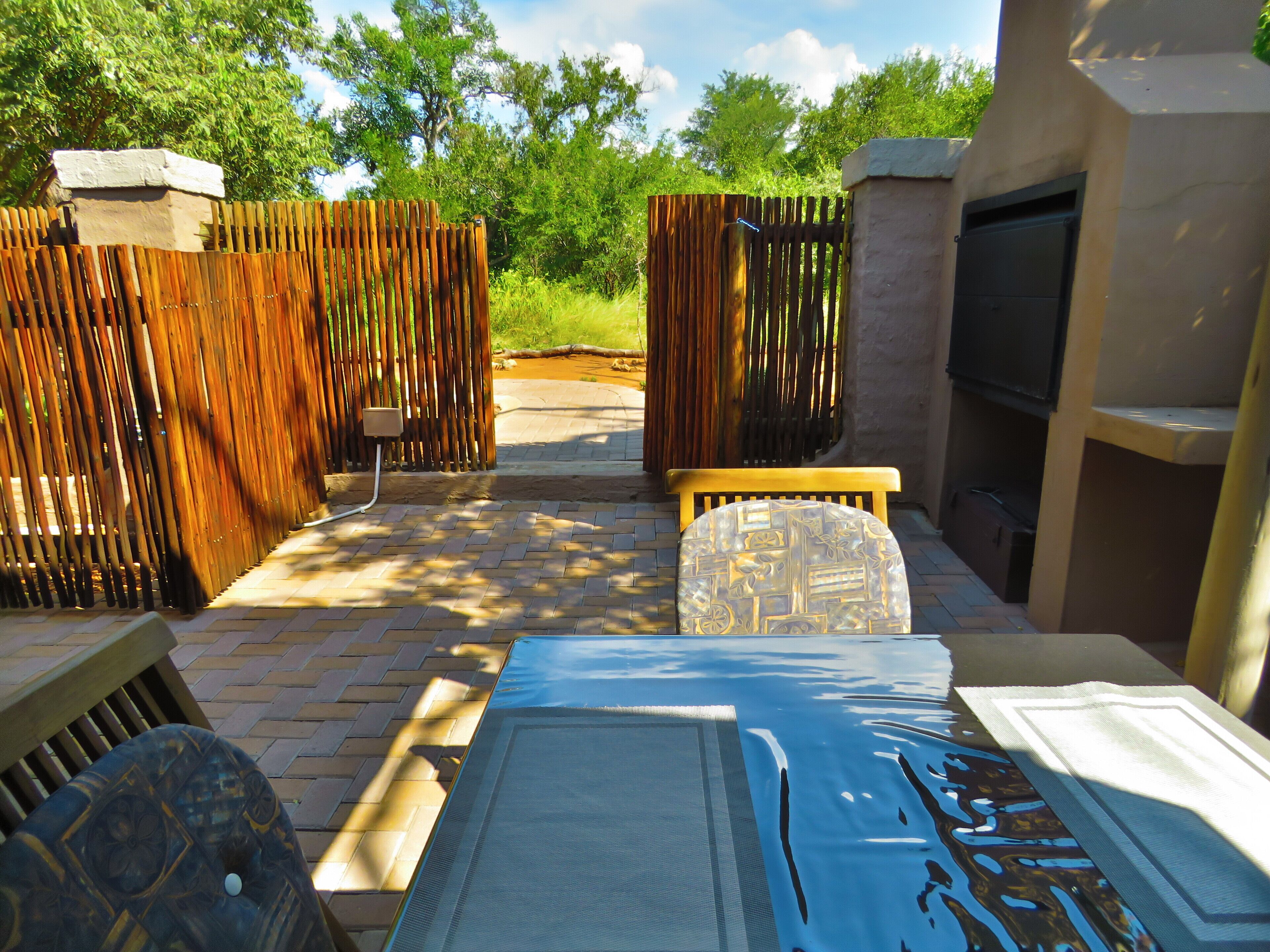 Une terrasse extérieure avec une piscine, des meubles en bois et un téléviseur fixé au mur.