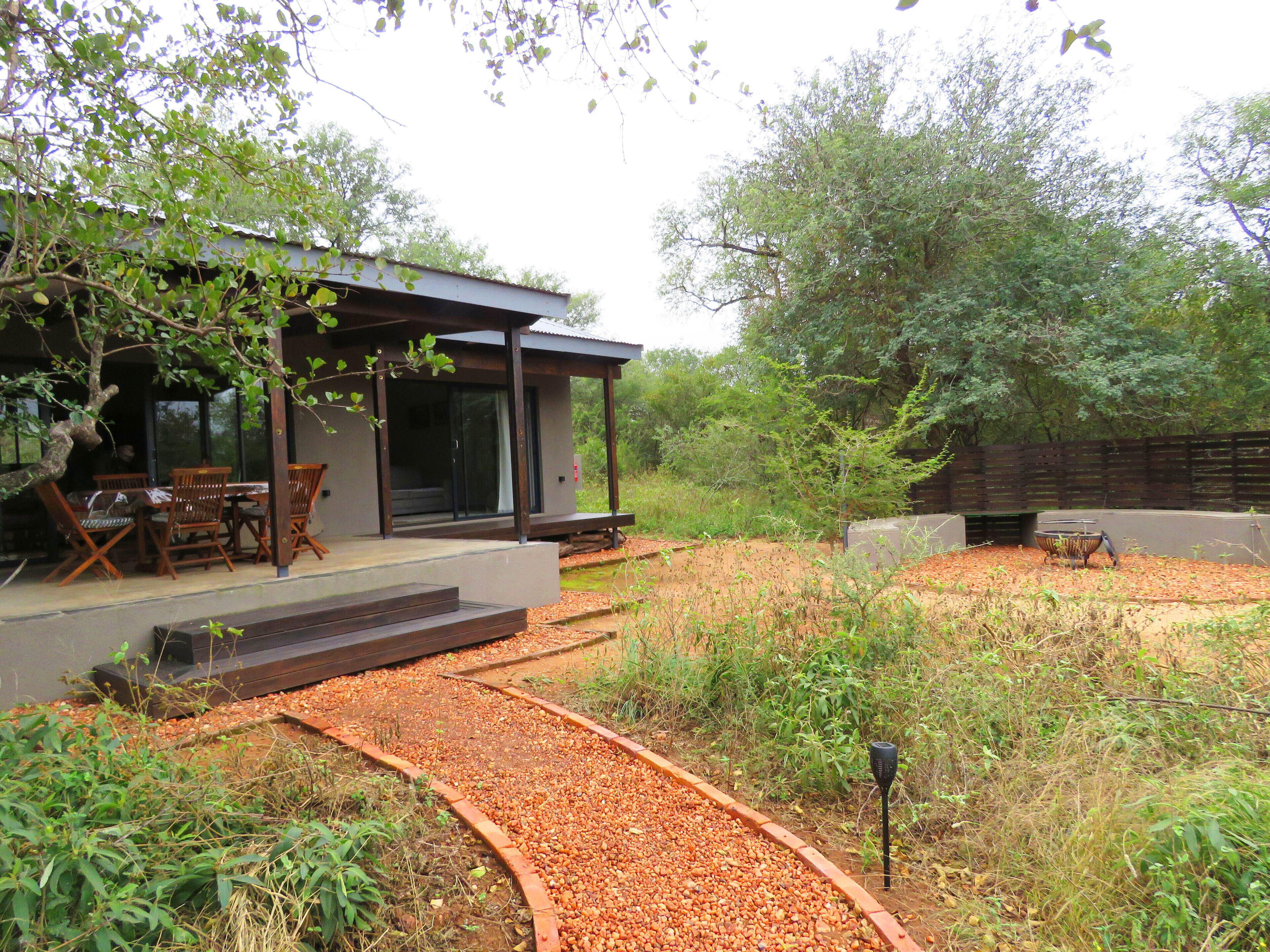 Una casa moderna con un porche cubierto, mobiliario de exterior y un sendero de grava.