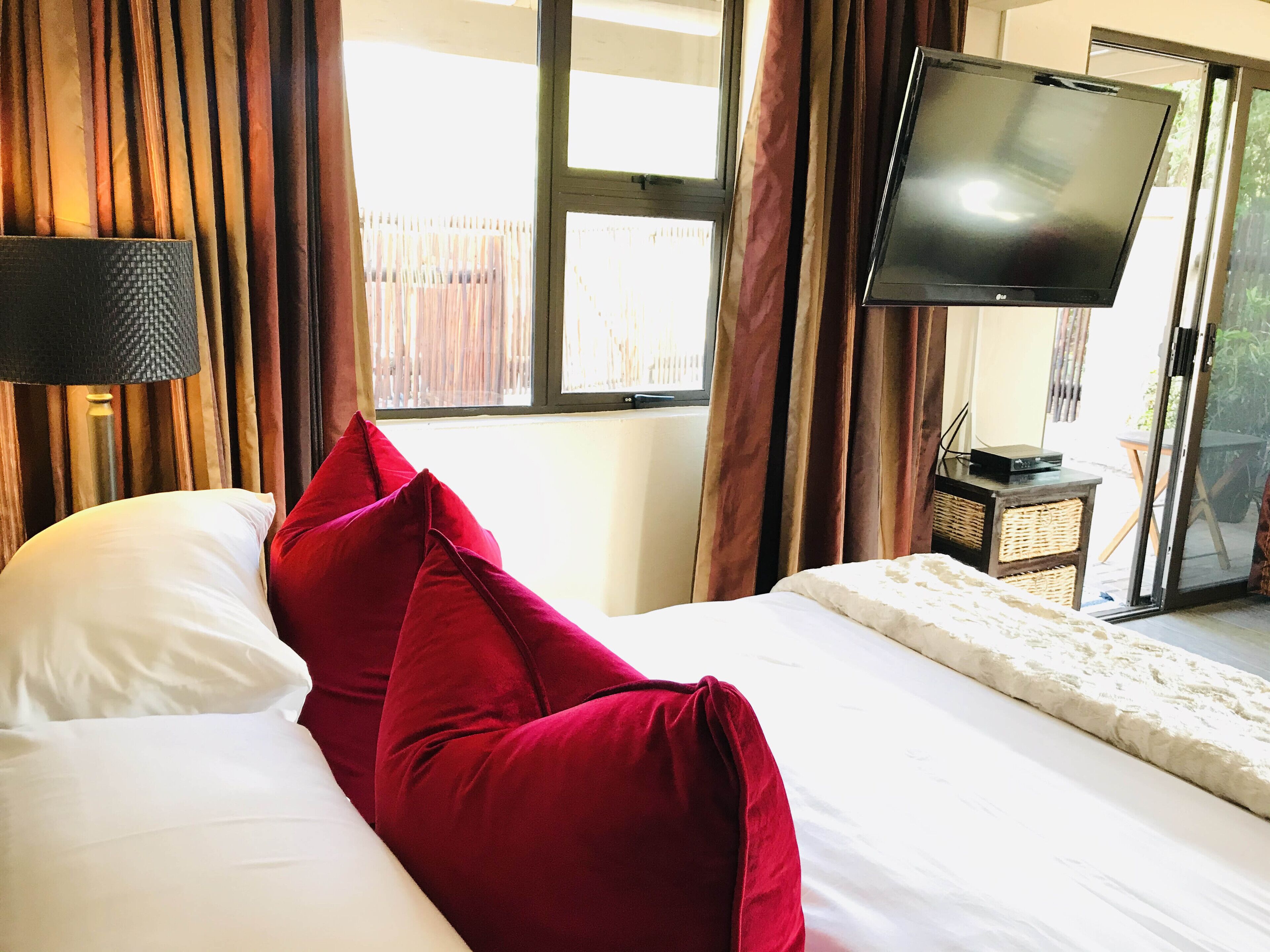 A hotel room with a bed, a television, and a window with curtains.