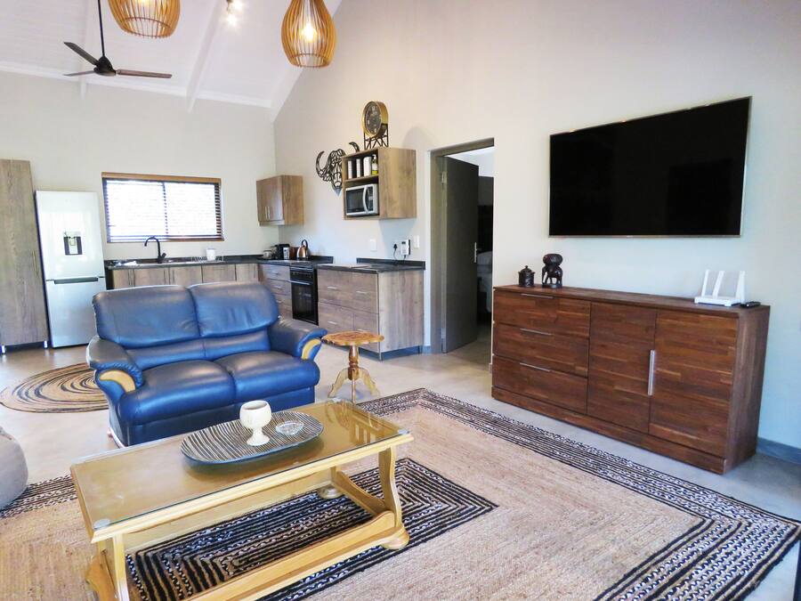 A modern living room with a blue sofa, a glass coffee table, and a wooden cabinet.