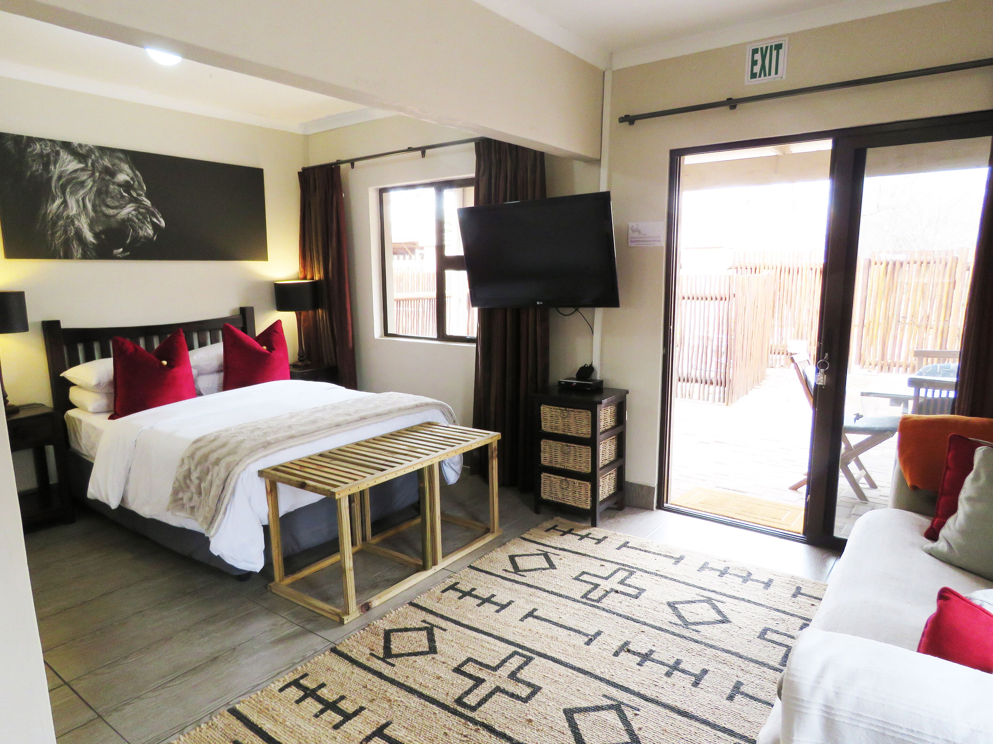 A hotel room with a bed, a TV, a small table, and a view of the outside.