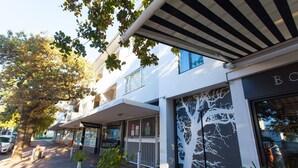 A building with a tree mural on the facade, a sign for 'BONDROMAT', and a covered outdoor seating area. - 109 on Dorp (Stellenbosch)