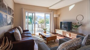 A modern living room with a leather sofa, a wooden coffee table, and a flat-screen TV. - 109 on Dorp (Stellenbosch)