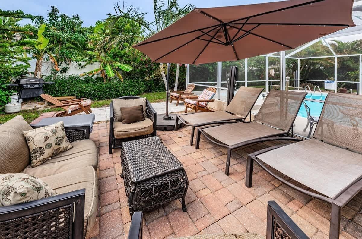 Un espace extérieur aménagé avec une piscine, des chaises longues, une table et un barbecue.