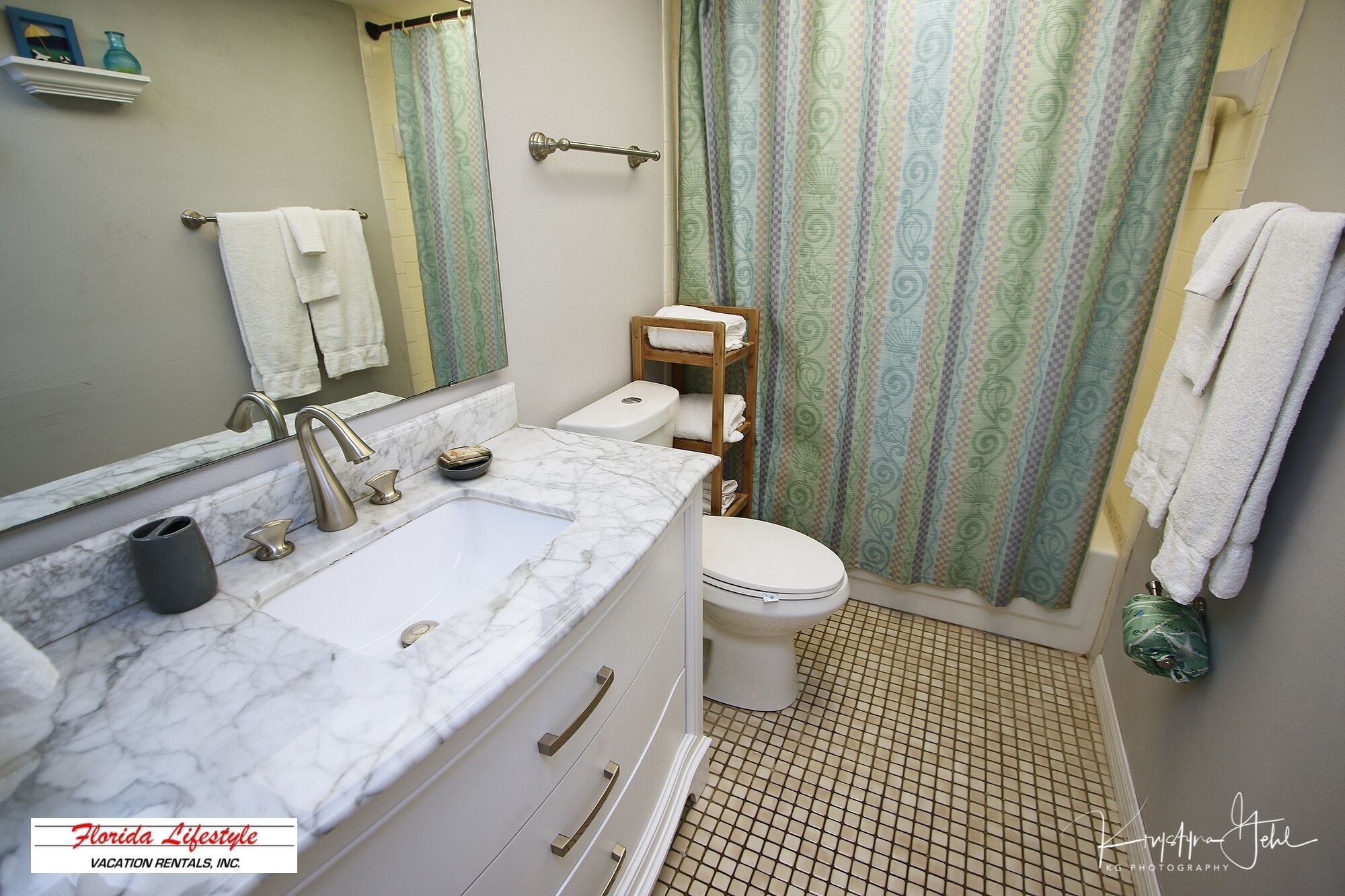 Une salle de bain avec un lavabo en marbre, des toilettes et un rideau de douche.