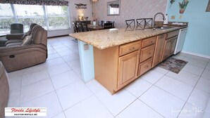 A spacious living area with a large island kitchen, a dining table, and a sofa.
