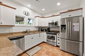 A modern kitchen with white cabinetry, stainless steel appliances, and a granite countertop.