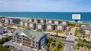 Un hotel sulla costa con diversi edifici, un parcheggio e una strada che porta alla spiaggia.