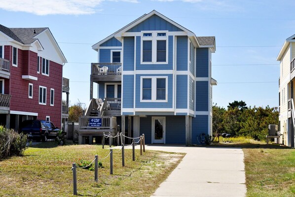 A multi-story residential building with a blue and white exterior, a visible front entrance, and a small porch area.