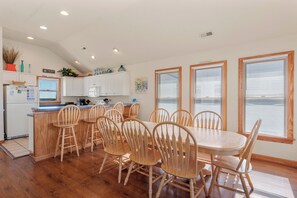 A modern kitchen with white cabinets, a wooden island, and a dining area with wooden chairs and a table.