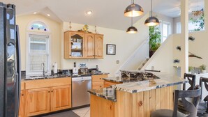 A kitchen with wooden cabinets, a marble countertop, and pendant lighting. - No Regrets: Semi-Oceanfront, Private Pool, 2 Spas (Nags Head)