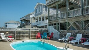 A pool area with a hot tub, multiple lounge chairs, and a wooden deck. - No Regrets: Semi-Oceanfront, Private Pool, 2 Spas (Nags Head)