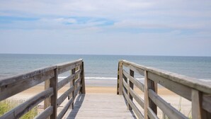 Une promenade en bois qui mène à une plage offrant une vue dégagée sur l’océan.