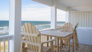Una terraza de madera con una mesa y sillas con vistas al océano.