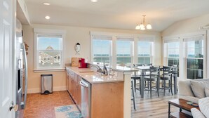 Una cocina amplia con una isla central, ventanas grandes y vista al mar.