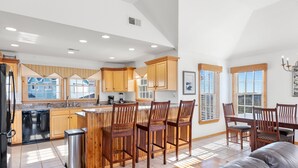 Una cocina amplia con armarios de madera, una isla central con taburetes de bar y un comedor con mesa y sillas.
