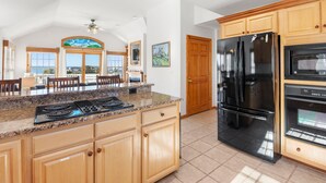 Una cocina con encimeras de granito, armarios de madera, un refrigerador negro y un horno empotrado.