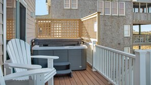 Eine Holzterrasse mit Whirlpool, weißen Adirondack-Stühlen und einem Holzzaun.