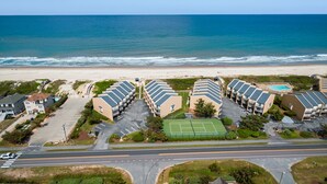 A coastal hotel with multiple buildings, a tennis court, and a beach view. - Trip's OBX: Oceanfront Townhome, Pool, Tennis (Nags Head)