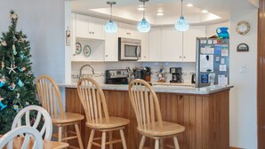 A kitchen with wooden chairs, a microwave, and a refrigerator.
