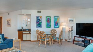 A living room with a dining area, a TV, and artwork on the walls.