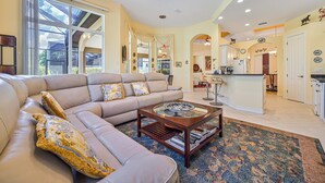 A spacious living room with a large L-shaped sectional sofa, a glass-top coffee table, and a patterned rug. - Luxurious Mediterranean Style Home! The finest finishes - Private Heated Pool (ESTERO)