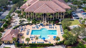 A large hotel with a central swimming pool, multiple balconies, and a parking area. - Luxurious Mediterranean Style Home! The finest finishes - Private Heated Pool (ESTERO)