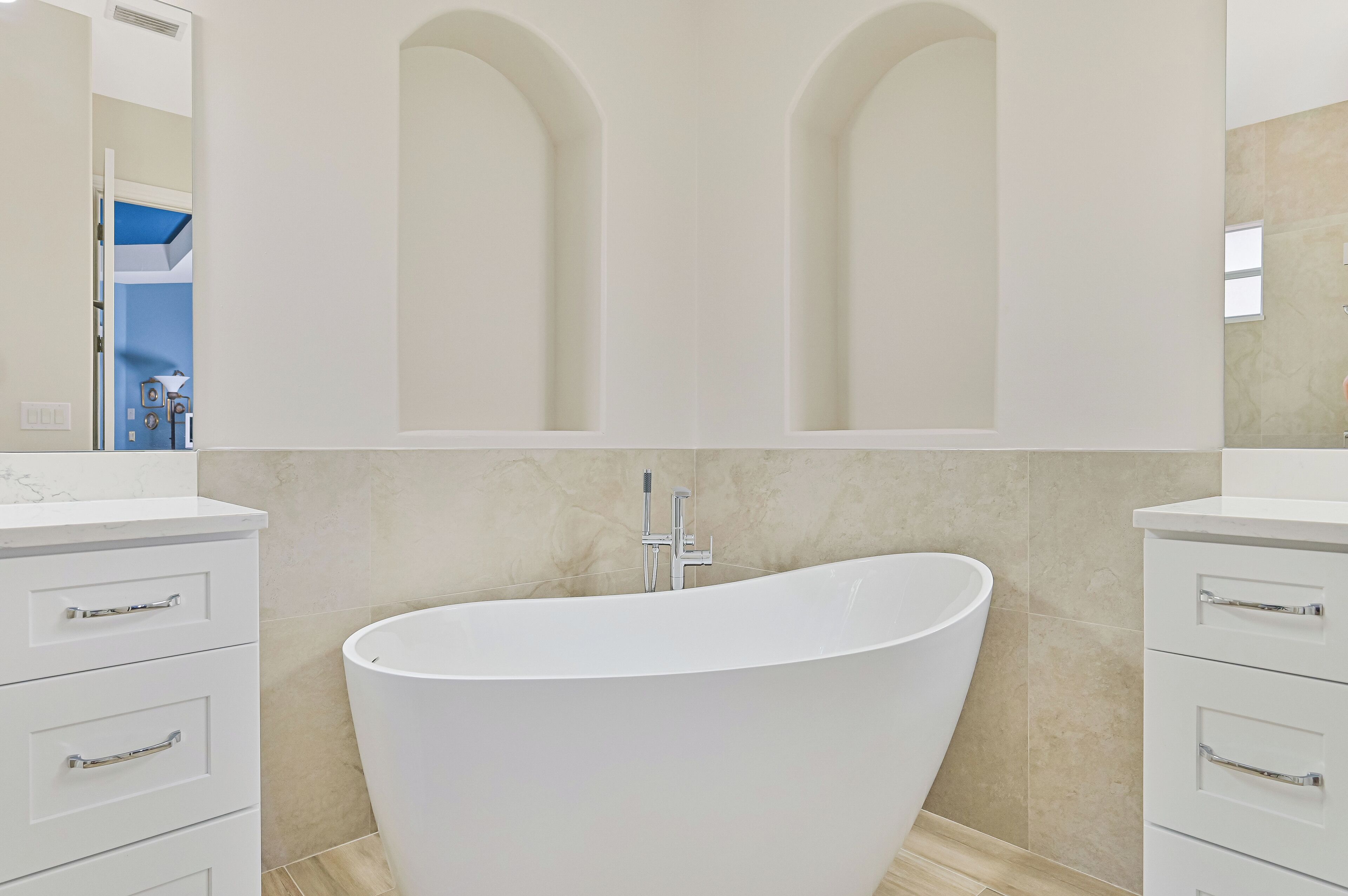 Une salle de bain moderne avec une baignoire sur pieds, des meubles blancs et un grand miroir au-dessus du meuble-lavabo.
