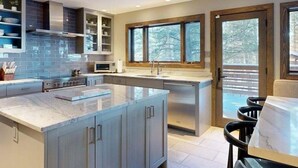 Una cocina moderna con una isla grande, electrodomésticos integrados y vistas al exterior.