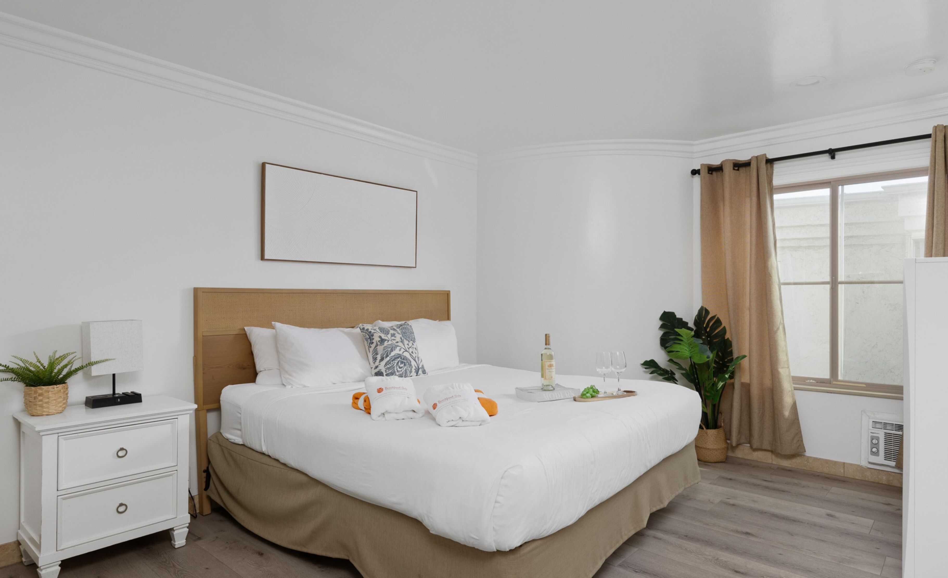 A neatly arranged hotel room with a bed, bedside table, and a window with curtains.