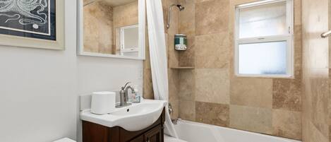 A bathroom with a bathtub, a sink, a mirror, and a shower.