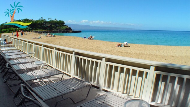 Ein Strand mit einer Holzterrasse und Liegestühlen.
