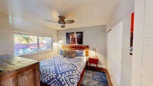 A bedroom with a bed, a nightstand, a window, a ceiling fan, and a door. - Moab Flats - 7, Downtown, half Block off Main Street (Moab)