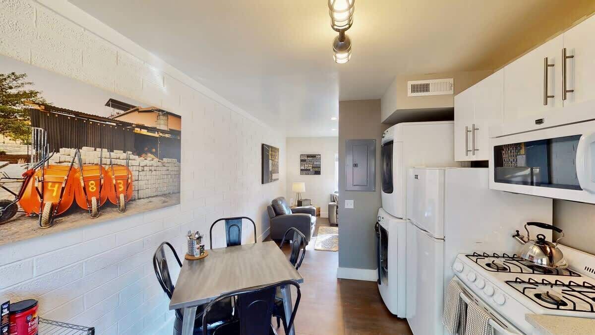 A compact kitchen with a gas stove, white cabinets, and a dining area with a table and chairs.