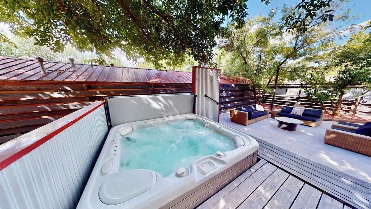 Een hottub op een houten terras, met buitenmeubels en een houten omheining.