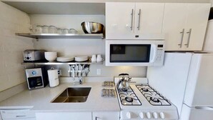 A kitchen with a gas stove, microwave, and white cabinets. - Moab Flats - 3, Escape to Moab! Walking Distance t (Moab)