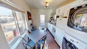 Cocina compacta con comedor, refrigerador, estufa y lavadora.