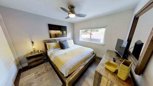 A bedroom with a bed, a television, a window, and a ceiling fan. - Moab Flats - 8, Southwest Luxe,  Escape from the world (Moab)