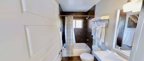 Un baño con bañera, inodoro y lavamanos.