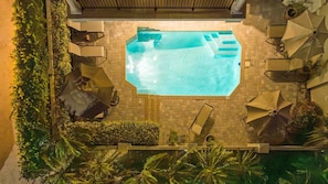 Une piscine extérieure entourée de verdure, avec des chaises longues et des parasols.