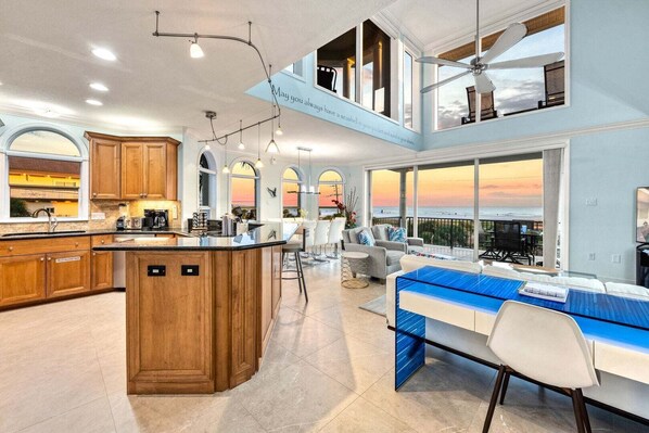 A spacious kitchen with wooden cabinets, a central island, and a dining area with a view of the ocean. - Admirals Watch | Ocean Views from Spacious Balconies, Heated Pool, and Steps to Siesta Key Beach (Siesta Key)