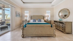 A spacious bedroom with a large bed, a dresser, a mirror, and a balcony with outdoor furniture.