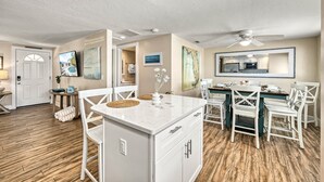 A spacious kitchen with white cabinetry, a dining area with white chairs, and a large island with a sink. - Casita Morning Star | Pet Friendly Home on Siesta Key, Heated Pool, Walk to Beach & South Village! (Siesta Key)