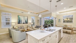 A spacious living room with a large sofa, a coffee table, and a dining area with a table set for four.