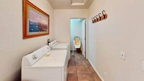A laundry room with a washing machine and dryer, a hallway leading to a door, and a coat rack on the wall. - Arches Abode - A3, 3 Bedroom Condo in Moab and Beautiful Views (Moab)