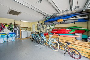 A garage with bicycles, kayaks, and a washing machine. - La Contento Casa | Private Heated Pool, Pet Friendly, Walk to Siesta Key Village and Beach (Siesta Key)