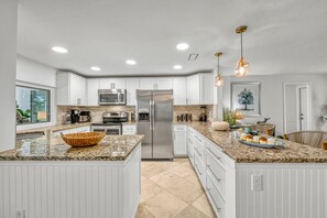 A modern kitchen with white cabinetry, granite countertops, stainless steel appliances, and pendant lighting. - La Contento Casa | Private Heated Pool, Pet Friendly, Walk to Siesta Key Village and Beach (Siesta Key)
